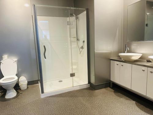 a bathroom with a shower and a toilet and a sink at Gamma Hotel in Auckland