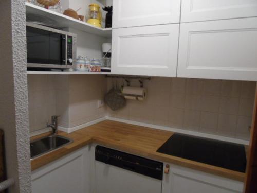 une cuisine avec des armoires blanches, un évier et un micro-ondes dans l'établissement Studio cosy 4 pers, proche télécabine & commerces - FR-1-561-42, à Valfréjus
