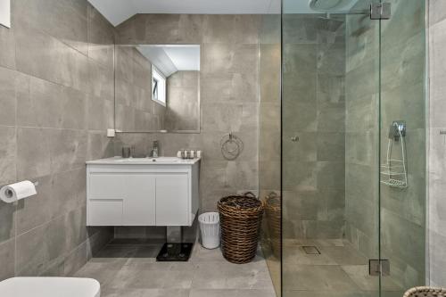 La salle de bains est pourvue d'un lavabo et d'une douche en verre. dans l'établissement StayCentral - Thornbury Entertainer Townhouse, à Melbourne