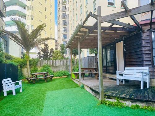 a backyard with benches and a wooden pergola at Gamma Hotel in Auckland