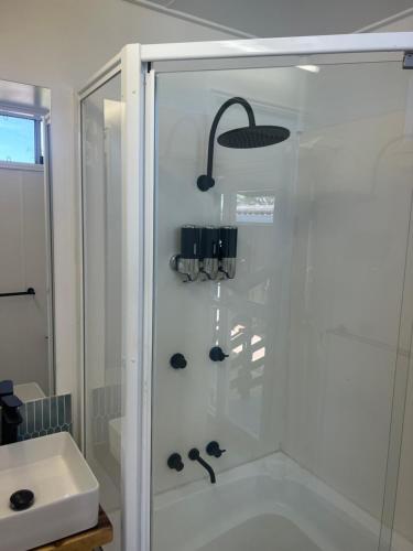 prysznic ze szklanymi drzwiami obok umywalki w obiekcie Hinchinbrook Riverview Retreat w mieście Upper Stone