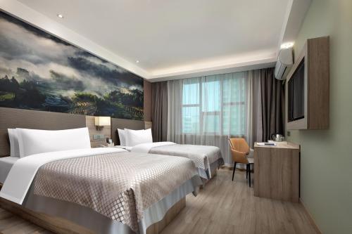 ein Hotelzimmer mit 2 Betten und einem Gemälde in der Unterkunft Morninginn, Zhushan Park in Loudi