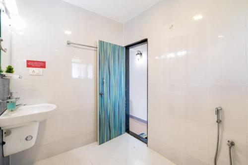 a white bathroom with a shower and a sink at 'Escape to the heavens with our sky view' 1BhK apartment,WIFI, Gym, pool & 5 min walk to Colva Beach in Colva
