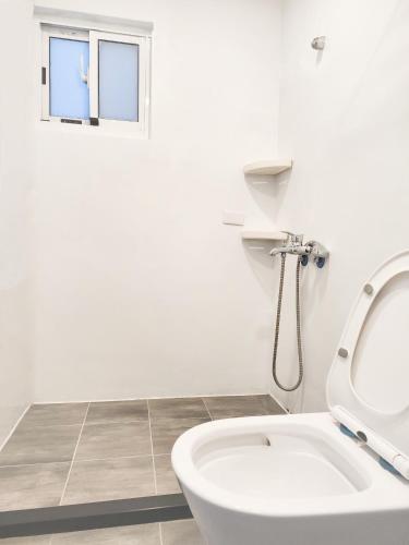 a white bathroom with a toilet and a window at Green Island Coastal Homestay in Green Island