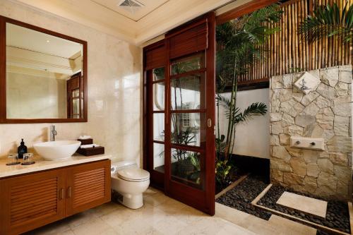 a bathroom with a toilet and a sink and a shower at Jimbaran Beach Villas by Nakula in Jimbaran