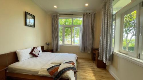 a bedroom with a bed and two windows at Villa Mui Ne Phan Thiet SeaView in Mui Ne