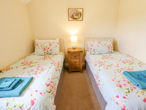 two twin beds in a room with a night stand at Westerby Lodge in Claythorpe