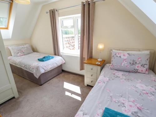 a small bedroom with two beds and a window at Holly Cottage in Alford