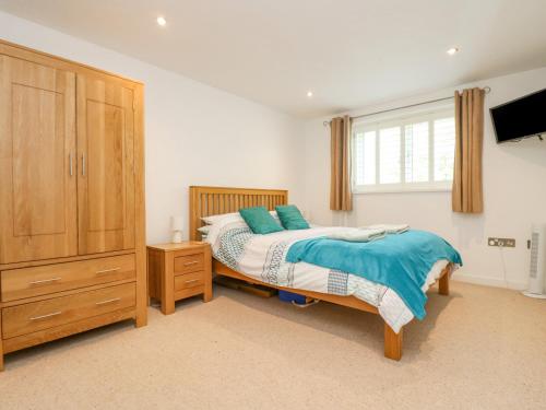 a bedroom with a bed and a dresser and a window at Rock Pool in Downderry