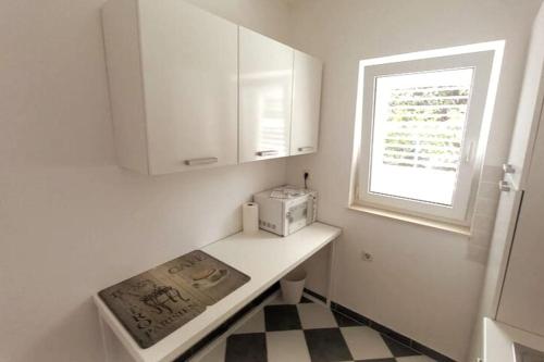 a small white kitchen with a counter and a window at Rosa apartment Mirca in Mirce