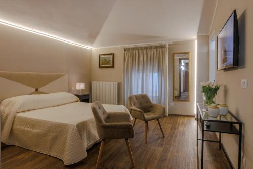a bedroom with a bed and two chairs at Albergo Alassio in Montecatini Terme