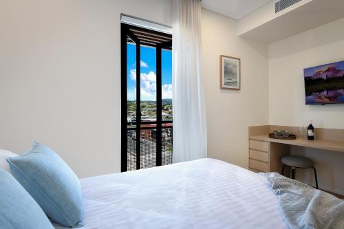a bedroom with a bed and a desk and a window at Nova Kiama in Kiama