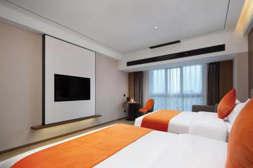 a hotel room with two beds and a flat screen tv at Morningup Hotel, Wugang in Wugang