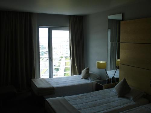a hotel room with two beds and a window at VIP Executive Azores Hotel in Ponta Delgada