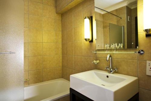een badkamer met een wastafel, een bad en een spiegel bij Mercure Hotel Windhoek in Windhoek