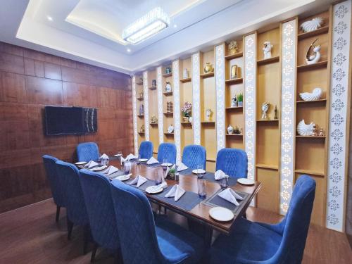 a conference room with a long table and blue chairs at Mariton Hotel in Jalandhar