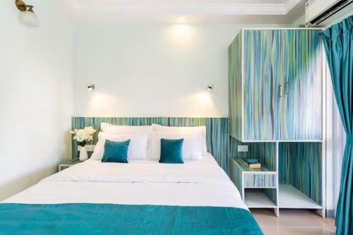 1 dormitorio con 1 cama grande de color azul y blanco en 'Serene Escape' Top Floor 1BHK Apartment with AC, Wi-Fi, Gym & Pool, 5-Minute Walk to the Beach, and Captivating Tree and Garden Views, en Colva