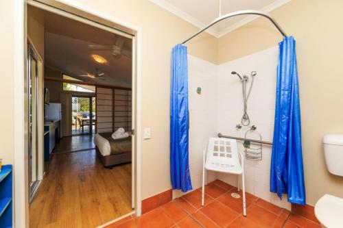 a bathroom with blue shower curtains and a toilet at Reflections Brunswick Head - Holiday Park in Brunswick Heads