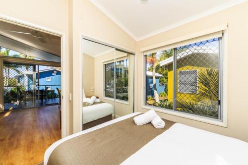 a bedroom with a bed and large windows at Reflections Brunswick Head - Holiday Park in Brunswick Heads