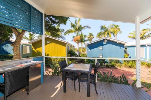 a patio with a table and chairs on a deck at Reflections Brunswick Head - Holiday Park in Brunswick Heads