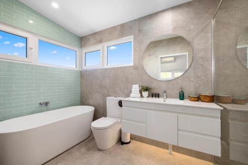 a bathroom with a tub and a sink and a mirror at Tea Trees in Woolgoolga