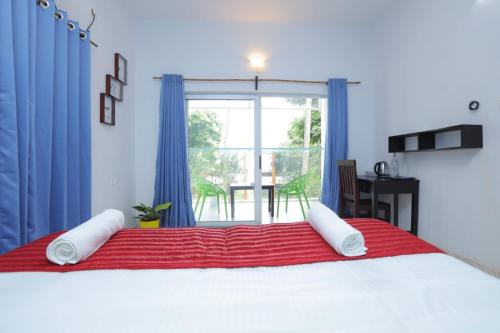 a bedroom with a large bed with blue curtains and a window at Sky Frame Beach Resort in Varkala
