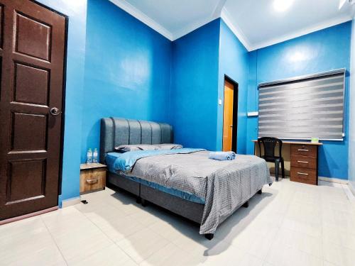 a blue bedroom with a bed and a wooden door at TREX Homestay_Batu Pahat in Batu Pahat