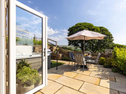 a patio with an umbrella and a table and chairs at Walton House Cottage in Chapel en le Frith