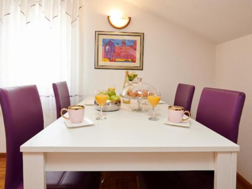 a dining room table with purple chairs and a white table at Guesthouse Ana Trogir Old Town in Trogir