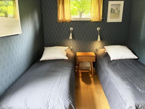 two twin beds in a room with a night stand and a table at Newly built cozy cottage on the east side of Öland in Färjestaden