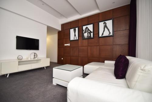 ein Wohnzimmer mit 2 weißen Sofas und einem TV in der Unterkunft Sesto Senso in Trebinje