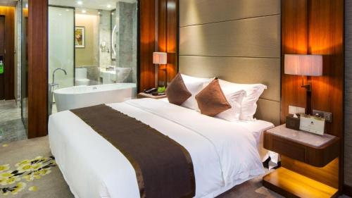 a bedroom with a large bed and a bath tub at Zhuhai Palm Spring Hotel in Zhuhai