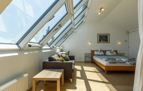 バダチョニトマイにあるBazalt Apartmanのベッド1台、ソファ、窓が備わる屋根裏部屋です。