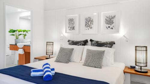 een slaapkamer met een groot wit bed met 2 lampen bij Belle Escapes presents 14 Alamanda Resort Where Pure Luxury meets the Coral Sea in Palm Cove