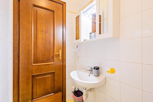 ein Badezimmer mit einem Waschbecken und einer Holztür in der Unterkunft La Santa Maria in Cuneo