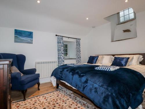 a bedroom with a bed and a blue chair at Downrow Barn in Tintagel