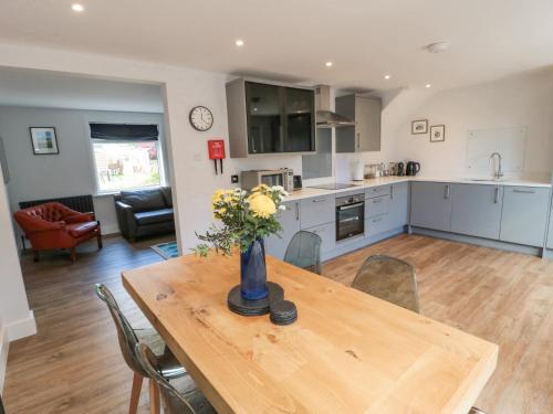 a kitchen and dining room with a table with flowers on it at 3 St Cuthberts Garth in Bamburgh