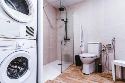 a bathroom with a washing machine and a toilet at 1linea Canteras in Las Palmas de Gran Canaria