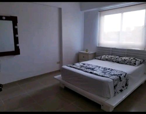 a white bedroom with a bed and a window at Apartamento a 5 minutos Zona Colonial in Santo Domingo