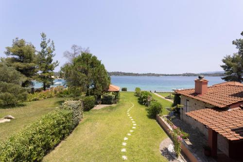 a garden of a house with a view of the water at Villa Egeo - Beachfront Paradise, Starlink, BBQ in Vourvourou