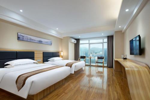 Una habitación de hotel con dos camas y un televisor de pantalla plana. en Morninginn, Zhangjiajie Tianmen Mountain, en Zhangjiajie