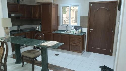 cocina con armarios de madera y encimera verde en Baran Homestay, en Mascate