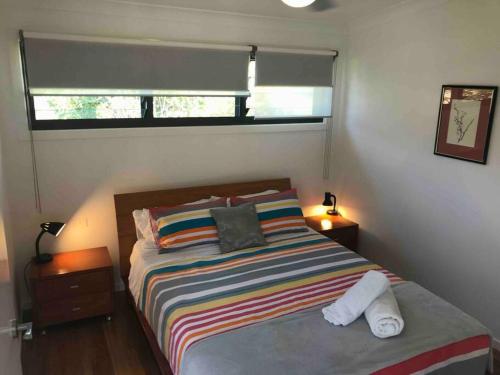 Coffs Harbour Sanctuary في كوفس هاربور: غرفة نوم مع سرير وبطانية مخططة ملونة