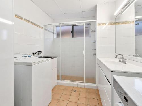 Un baño blanco con ducha y lavabo. en Blue Horizons Kingscliff with Pool, en Kingscliff