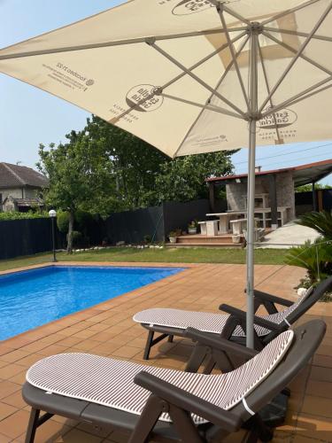 un par de sillas y una sombrilla junto a una piscina en Casa con vistas a Portugal, en Arbo