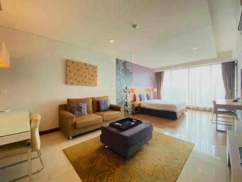 uma sala de estar com um sofá e uma mesa em The H Tower Rasuna Suites Kuningan jakarta by Villaloka em Jakarta