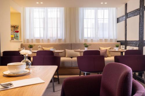 a restaurant with purple chairs and tables and a couch at Hotel Le Colombier in Colmar