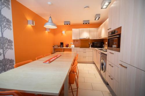 una cocina con una mesa larga y paredes de color naranja en Gite de la Baie - Morgat, en Crozon