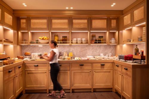 a woman standing in a kitchen preparing food at Hotel Le Colombier in Colmar