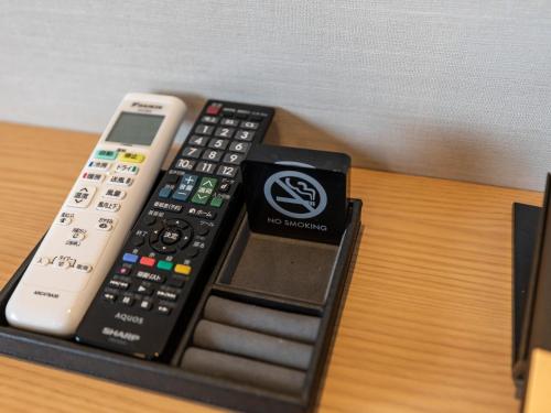 three remote controls sitting on top of a table at Tabist kiki HOTEL KYOTO Gojo Karasuma in Kyoto